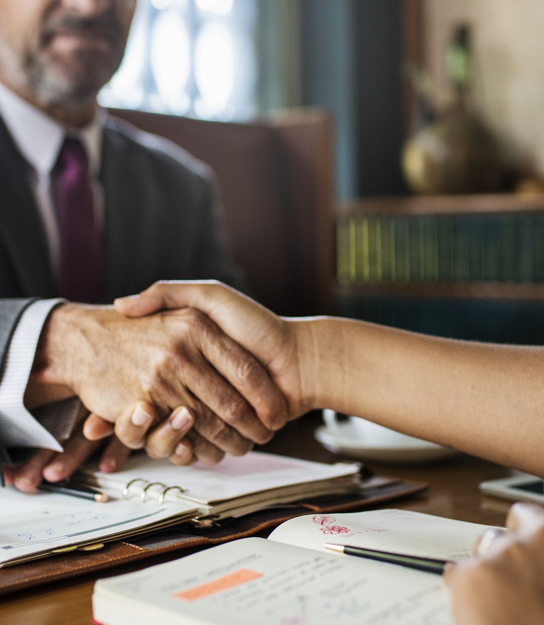 Attorney shaking hands with a client across a desk