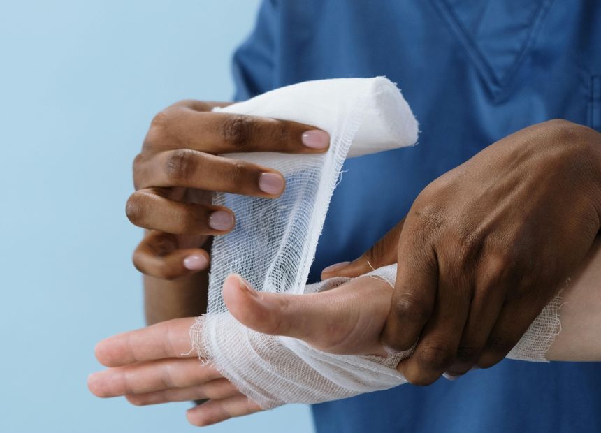Clinician wrapping an injured hand in gauze